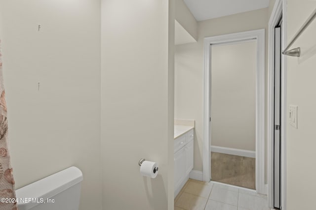 half bath featuring toilet, tile patterned flooring, baseboards, and vanity