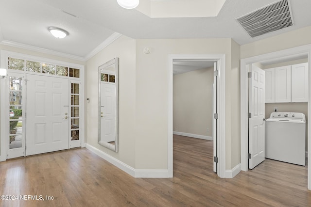 foyer with visible vents, baseboards, ornamental molding, light wood-type flooring, and washer / clothes dryer