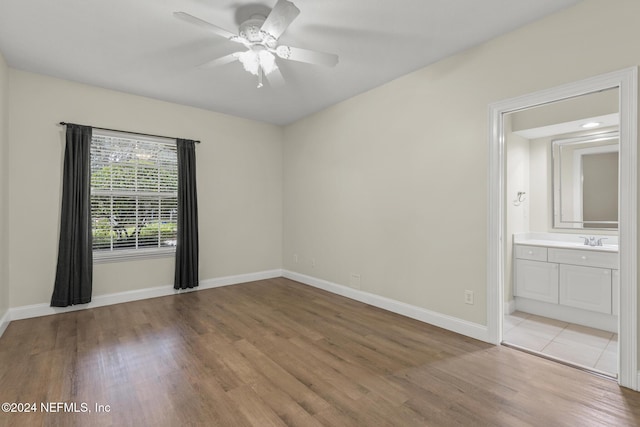 empty room with light wood-style floors, a sink, baseboards, and a ceiling fan