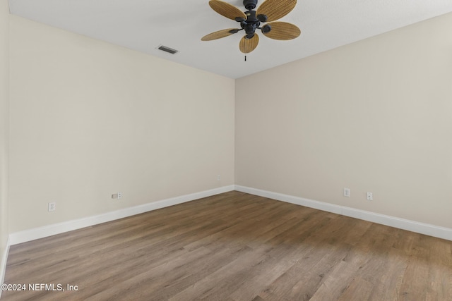 empty room featuring a ceiling fan, baseboards, visible vents, and wood finished floors