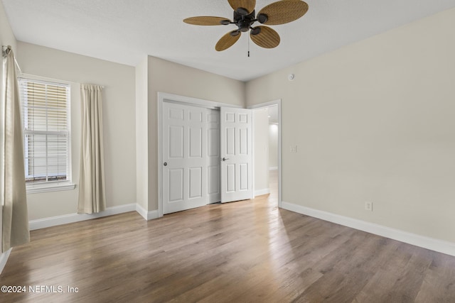 unfurnished bedroom featuring a ceiling fan, a closet, light wood finished floors, and baseboards