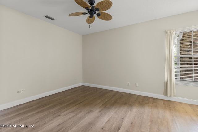 spare room featuring visible vents, ceiling fan, baseboards, and wood finished floors