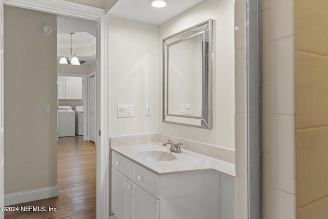 bathroom with washing machine and dryer, vanity, wood finished floors, a chandelier, and baseboards