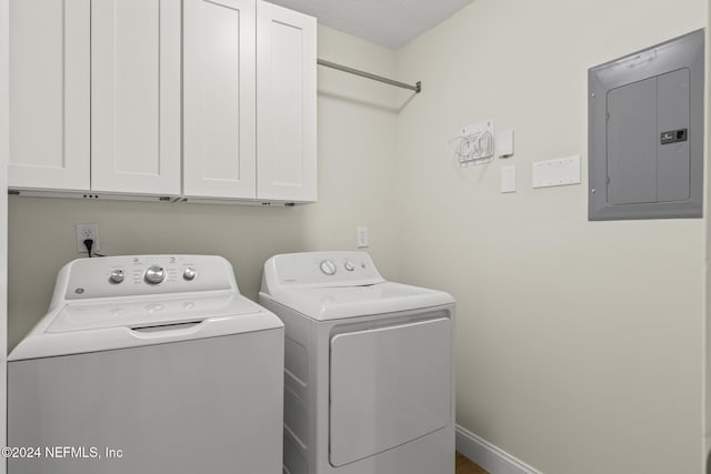 laundry area featuring baseboards, electric panel, cabinet space, and washing machine and clothes dryer