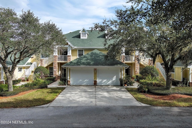 view of front of house featuring a garage, driveway, a shingled roof, stone siding, and stairway