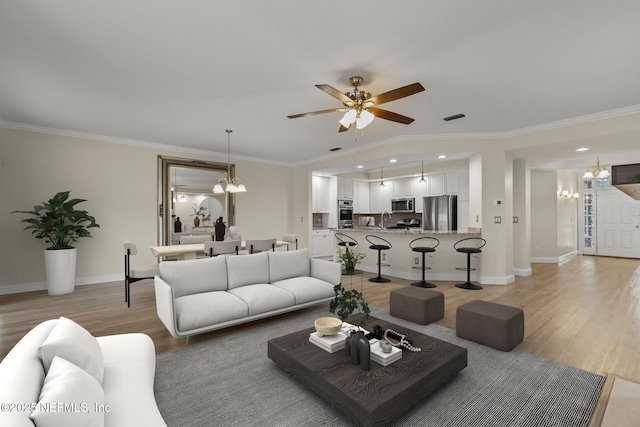 living area with light wood-style flooring, ornamental molding, and baseboards