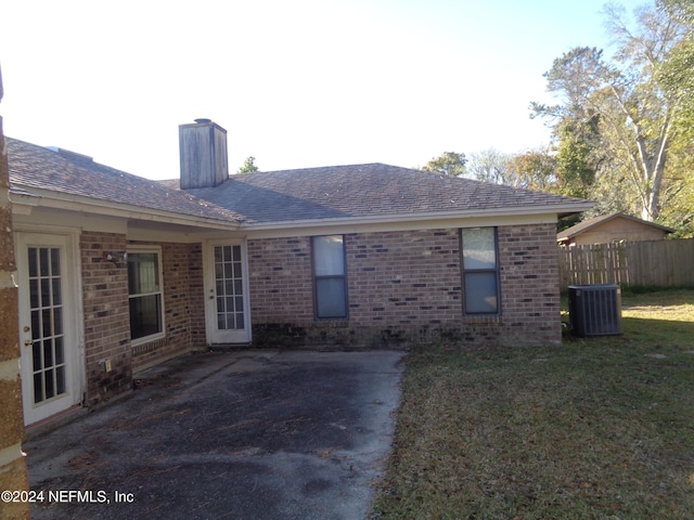 rear view of house featuring a lawn and central AC