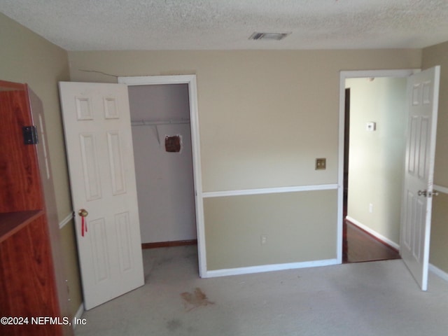 unfurnished bedroom featuring a closet, light colored carpet, and a textured ceiling