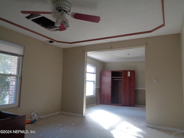 empty room with ceiling fan, light colored carpet, and a textured ceiling