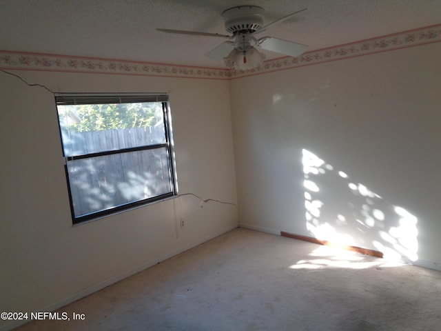 empty room with a textured ceiling, light colored carpet, and ceiling fan