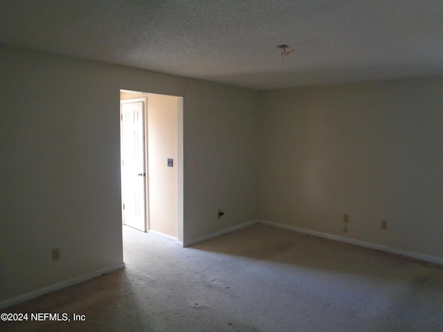 empty room with a textured ceiling and light carpet