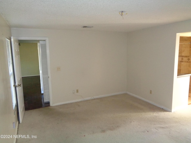 carpeted empty room featuring a textured ceiling