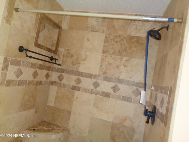 interior details featuring a textured ceiling and tiled shower