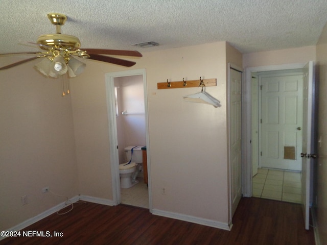 unfurnished bedroom featuring dark wood-type flooring, ensuite bathroom, ceiling fan, a textured ceiling, and a closet