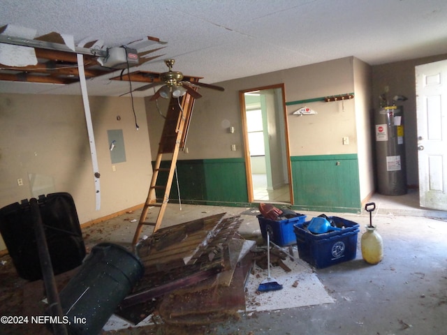 misc room featuring electric panel, ceiling fan, a textured ceiling, water heater, and concrete flooring