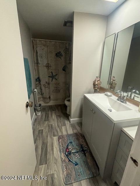 bathroom featuring curtained shower, toilet, vanity, and hardwood / wood-style flooring