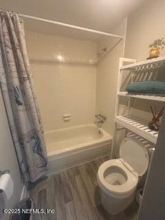 bathroom with hardwood / wood-style floors, shower / bathtub combination with curtain, and toilet