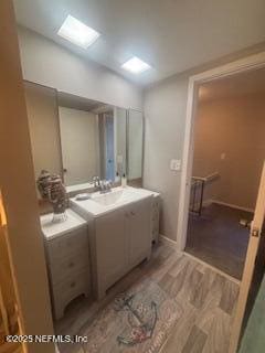 bathroom featuring vanity, a skylight, and hardwood / wood-style floors