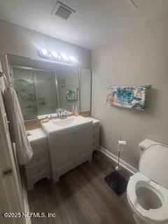 bathroom with hardwood / wood-style flooring, vanity, toilet, and a shower with shower door