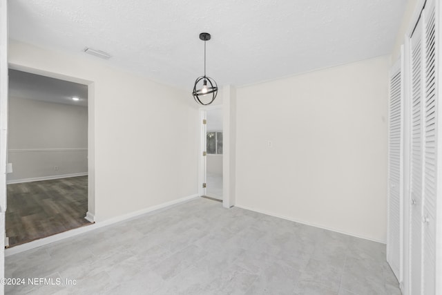 unfurnished dining area featuring a textured ceiling and an inviting chandelier