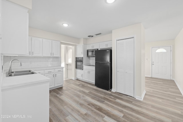 kitchen featuring sink, light hardwood / wood-style floors, white cabinetry, and black appliances