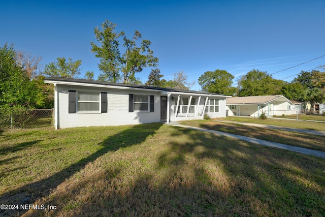 ranch-style home featuring a sunroom and a front lawn