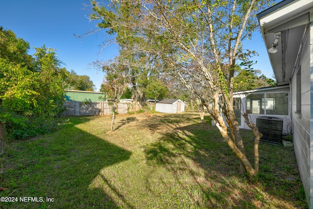 view of yard featuring central AC unit and a storage shed