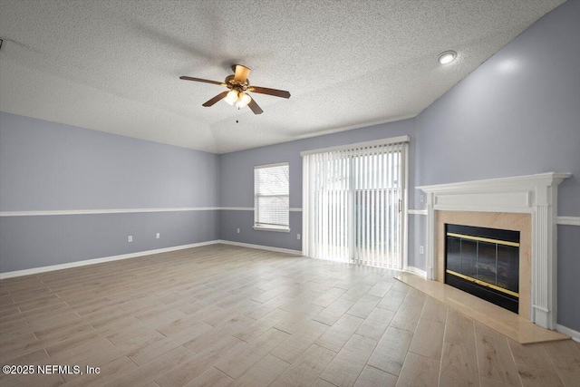 unfurnished living room featuring ceiling fan, a high end fireplace, vaulted ceiling, and a textured ceiling