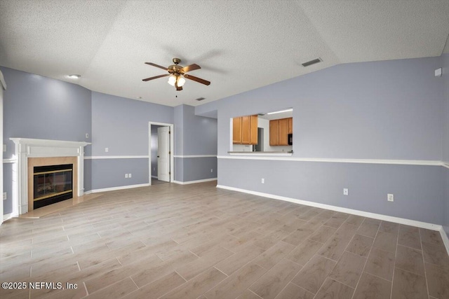 unfurnished living room with lofted ceiling, a fireplace, and ceiling fan