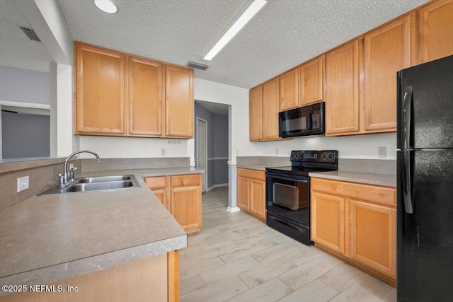 kitchen featuring light brown cabinetry, sink, a textured ceiling, and black appliances