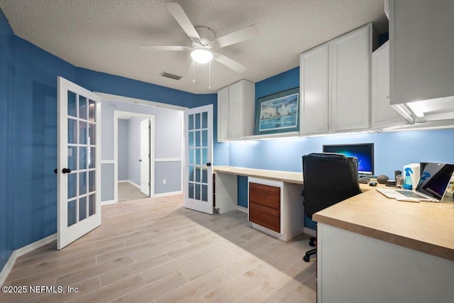 office with ceiling fan, french doors, a textured ceiling, and light wood-type flooring