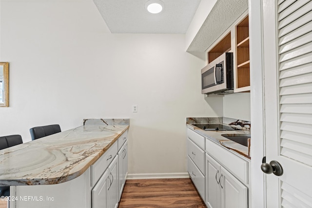 kitchen featuring a kitchen breakfast bar, white cabinetry, dark hardwood / wood-style flooring, and sink