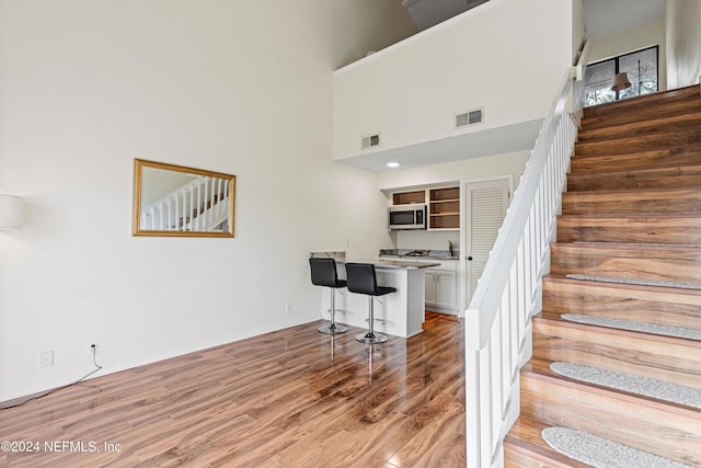 staircase with a high ceiling and hardwood / wood-style flooring