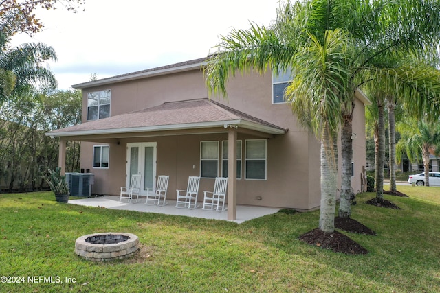 back of property with a yard, an outdoor fire pit, and central AC