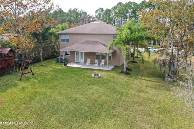 back of house featuring a lawn, a fire pit, a playground, cooling unit, and a patio