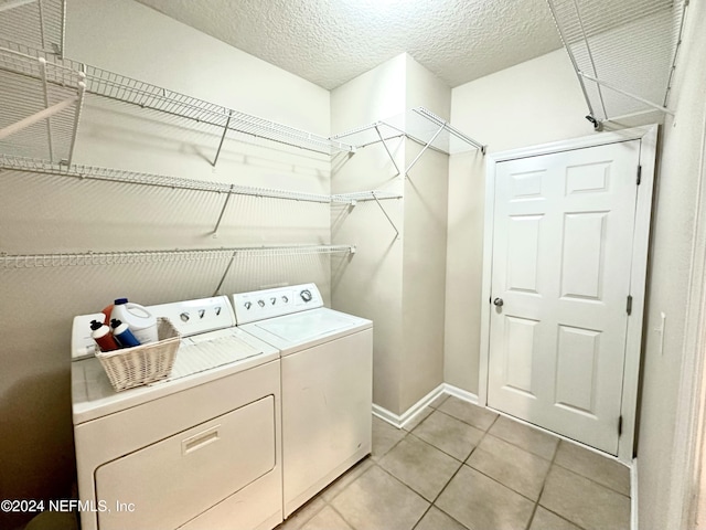 clothes washing area with light tile patterned floors, a textured ceiling, and washer and clothes dryer