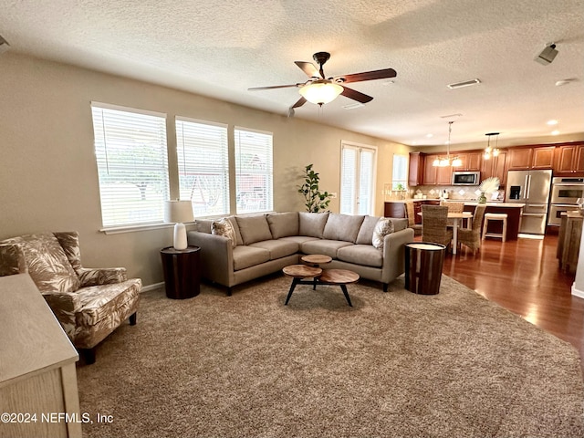 living room featuring a textured ceiling, dark hardwood / wood-style flooring, and ceiling fan