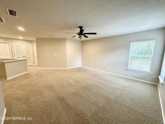 carpeted empty room with ceiling fan and a textured ceiling