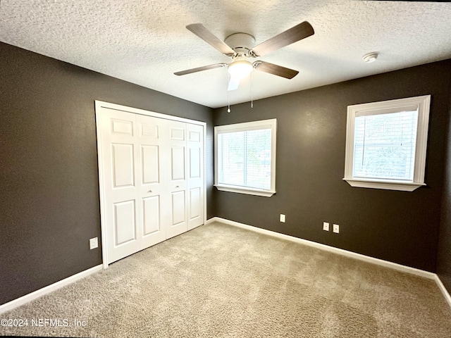 unfurnished bedroom with multiple windows, ceiling fan, a closet, and light colored carpet