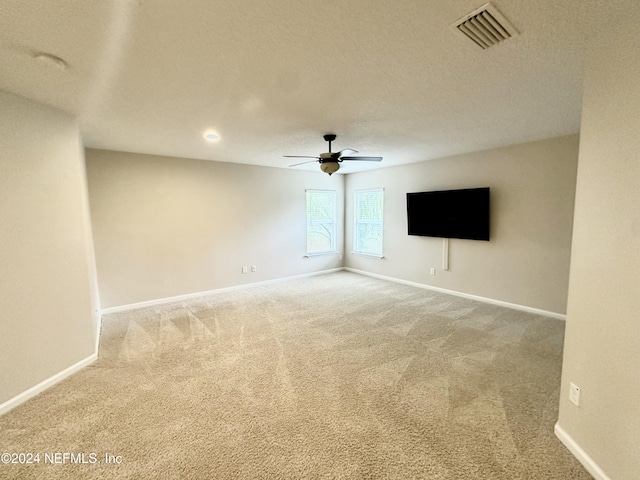 spare room featuring carpet flooring, ceiling fan, and a textured ceiling