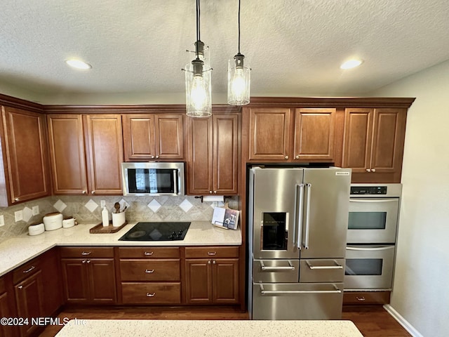 kitchen featuring pendant lighting, a textured ceiling, stainless steel appliances, and tasteful backsplash