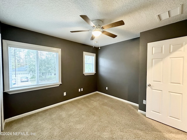 unfurnished bedroom with ceiling fan, carpet, and a textured ceiling