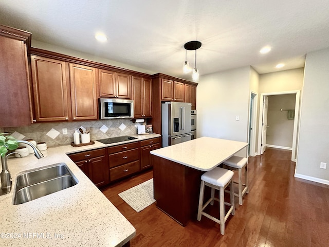 kitchen featuring a center island, sink, hanging light fixtures, stainless steel appliances, and dark hardwood / wood-style floors