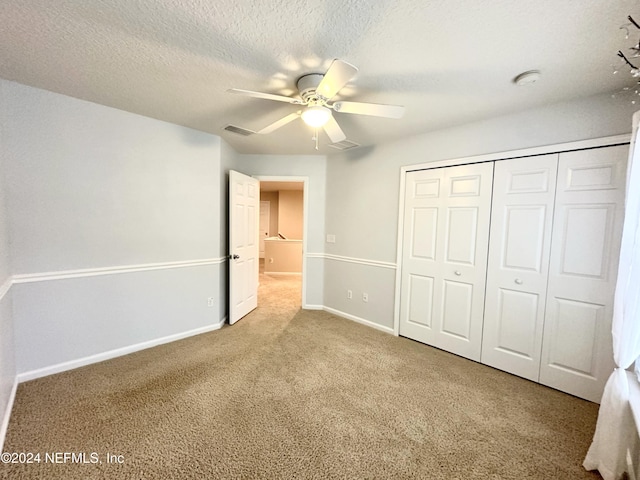 unfurnished bedroom with carpet flooring, ceiling fan, a closet, and a textured ceiling