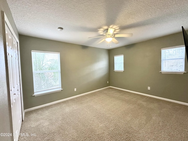 unfurnished room featuring a textured ceiling, carpet floors, and ceiling fan