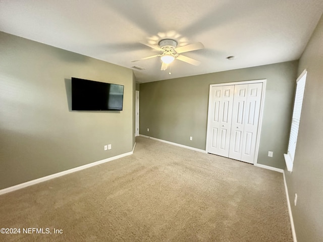 unfurnished bedroom featuring ceiling fan, a closet, and carpet floors