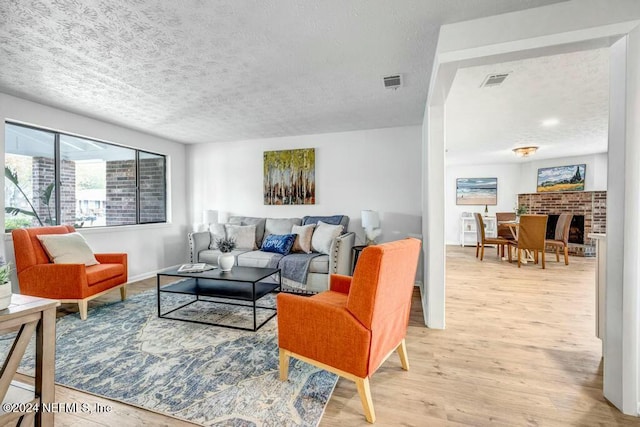 living room with a fireplace, light hardwood / wood-style floors, and a textured ceiling