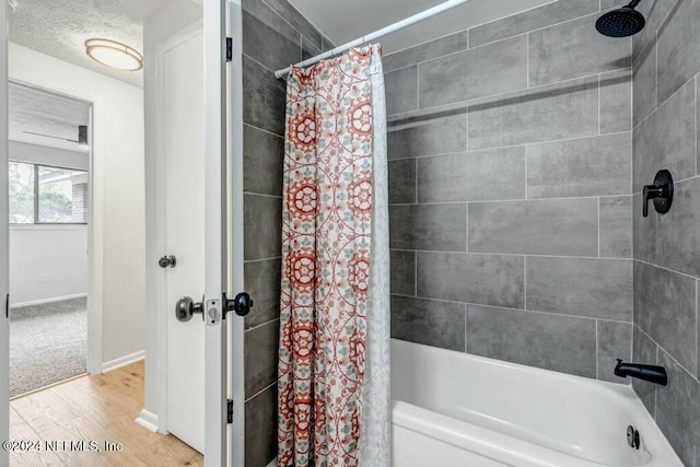 bathroom featuring hardwood / wood-style floors, shower / bath combination with curtain, and a textured ceiling