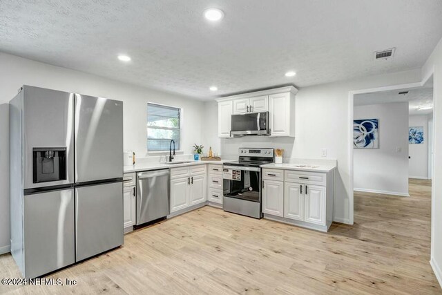 kitchen featuring white cabinetry, sink, stainless steel appliances, and light hardwood / wood-style flooring