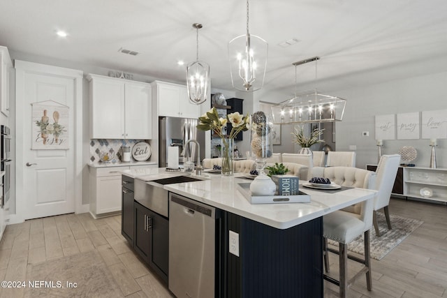 kitchen featuring pendant lighting, white cabinetry, appliances with stainless steel finishes, and a large island with sink